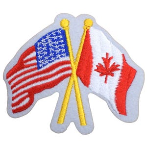 May include: Embroidered patch featuring the flags of the United States and Canada crossed. The American flag has red and white stripes with a blue field of white stars. The Canadian flag is red with a white maple leaf. The flag poles are yellow.