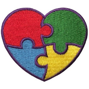 May include: Embroidered patch in the shape of a heart, composed of four puzzle pieces. The pieces are red, green, blue, and yellow, outlined in purple. The patch is designed to be ironed on or sewn onto fabric.