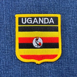 May include: A yellow, red, and black embroidered patch with the word "UGANDA" in white letters and a black and white image of a crane in a white circle.