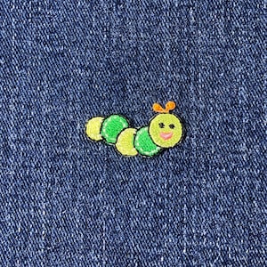 May include: Embroidered caterpillar patch in yellow, green, and pink, with a smiling face and orange antennae. The patch is on a blue denim background. This patch is perfect for adding to clothing or accessories.