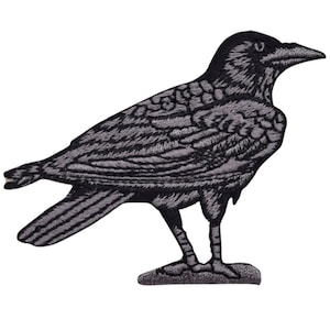 May include: A black and gray embroidered iron-on patch of a crow with its wings spread out.