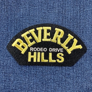 May include: Black embroidered patch with gold lettering that reads "Beverly Hills Rodeo Drive".