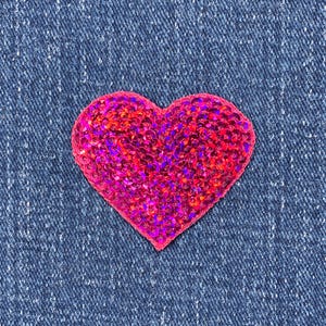 May include: A pink heart-shaped sequin patch. The sequins are iridescent and sparkle in the light.