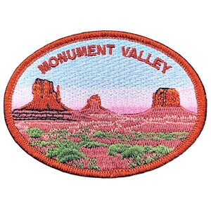 May include: Embroidered patch featuring a Monument Valley landscape with red rock formations, green shrubbery, and a blue and pink sky. The patch is oval-shaped with the words "MONUMENT VALLEY" in red lettering.