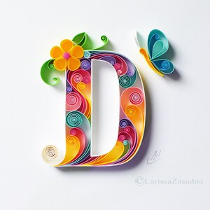 May include: A colorful paper quilling art piece depicting the letter D with a flower and butterfly design. The letter is made of curled paper strips in shades of pink, yellow, blue, green, and purple.