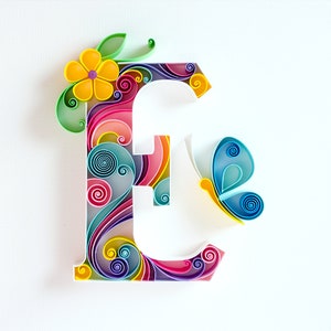 May include: A colorful paper craft letter E with swirls and a butterfly. The letter is made of paper in shades of pink, blue, yellow, green, and purple.