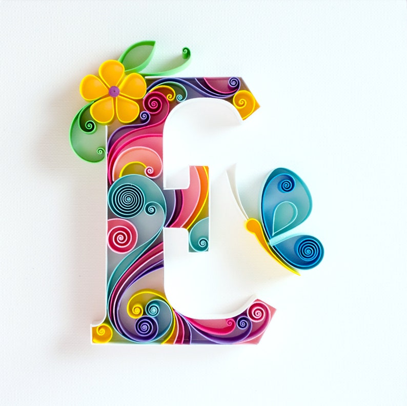 May include: A colorful paper craft letter E with swirls and a butterfly. The letter is made of paper in shades of pink, blue, yellow, green, and purple.