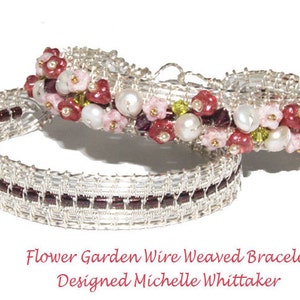 Könnte beinhalten: Zwei silberne, drahtgeflochtene Armbänder mit Blumenmuster. Die Armbänder sind mit rosa, roten und weißen Perlen sowie grünen und violetten Akzenten verziert. Die Armbänder sind übereinander gelegt. "Flower Garden Wire Weaved Bracelet Designed Michelle Whittaker" steht unter den Armbändern.