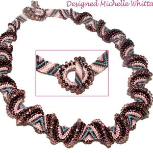 Op de afbeelding: Een kralenketting met een spiraalvormig ontwerp in tinten roze, bruin en turquoise. De ketting is gemaakt met kleine kralen en heeft een sluiting. "Designed Michelle Whittaker" staat bovenaan de afbeelding.