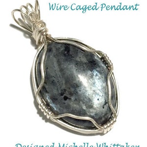 May include: A silver wire-wrapped pendant featuring a dark gray oval gemstone. The pendant is designed with a simple, elegant style, and the gemstone is set in a cage of silver wire. The pendant is labeled "Wire Caged Pendant" and "Designed Michelle Whittaker".