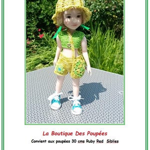 Peut inclure: Une poupée vêtue d'un ensemble crocheté jaune et vert, comprenant un chapeau, un haut, un short et un sac. Le short est orné d'un motif floral, et la poupée porte des baskets bleues et blanches. Le fond est un jardin verdoyant.