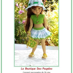 Peut inclure: Une poupée vêtue d'un ensemble crocheté vert, comprenant un haut, une jupe et un chapeau, avec un sac assorti et des sandales jaunes. La poupée a de longs cheveux bruns. L'ensemble est conçu pour des poupées de 36 cm.