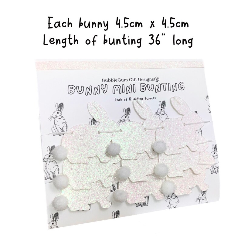 K&ouml;nnte beinhalten: Eine wei&szlig;e Glitzer-Hasen-Mini-Girlande mit 12 Hasen und wei&szlig;en Pompons. Jeder Hase ist 4,5 cm x 4,5 cm gro&szlig; und die Girlande ist 91,44 cm lang. Die Verpackung tr&auml;gt den Schriftzug "BubbleGum Gift Designs&reg; Bunny Mini Bunting Pack of 12 glitter bunnies".