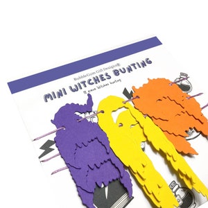 Puede incluir: Un conjunto de 12 recortes de papel con tem&aacute;tica de brujas de color morado, amarillo y naranja para una mini guirnalda de brujas. El paquete dice "BubbleGumGift Designs&reg; Mini Witches Bunting 12 piece witches bunting"
