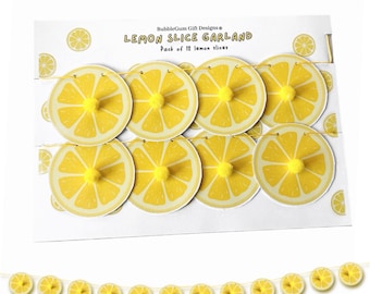 May include: A yellow lemon slice garland with 12 paper lemon slices and yellow pom-poms. The garland is strung on a yellow string. The packaging says "Lemon Slice Garland" and "Pack of 12 lemon slices".