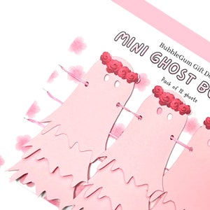Pode incluir: Guirlanda de fantasmas de papel rosa com uma coroa de rosas, parte de um conjunto de 12 mini decora&ccedil;&otilde;es de fantasmas. O texto na embalagem diz "BubbleGum Gift Decor Mini Ghost Banner Pack of 12 ghosts".