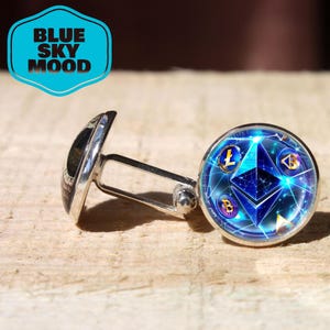 May include: Silver cufflinks with a round, blue face featuring cryptocurrency symbols. The cufflinks have a shiny finish and are set against a light-colored wooden surface. The text "BLUE SKY MOOD" is in a blue and white badge.