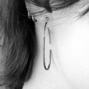 Pu&ograve; includere: Primo piano di un orecchio con pi&ugrave; piercing. La persona indossa un grande orecchino a cerchio d'argento nell'orecchio superiore.