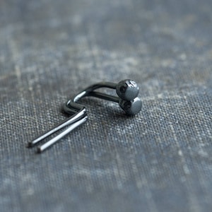 Könnte beinhalten: Ein silberner Gardinenhaken aus Metall mit zwei runden Knöpfen am Ende.