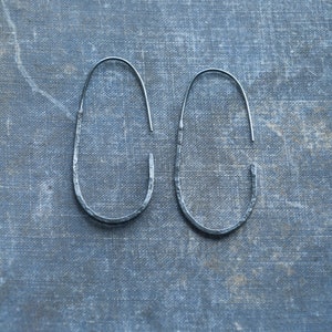 Pu&ograve; includere: Un paio di orecchini a cerchio ovali in argento con una texture martellata.