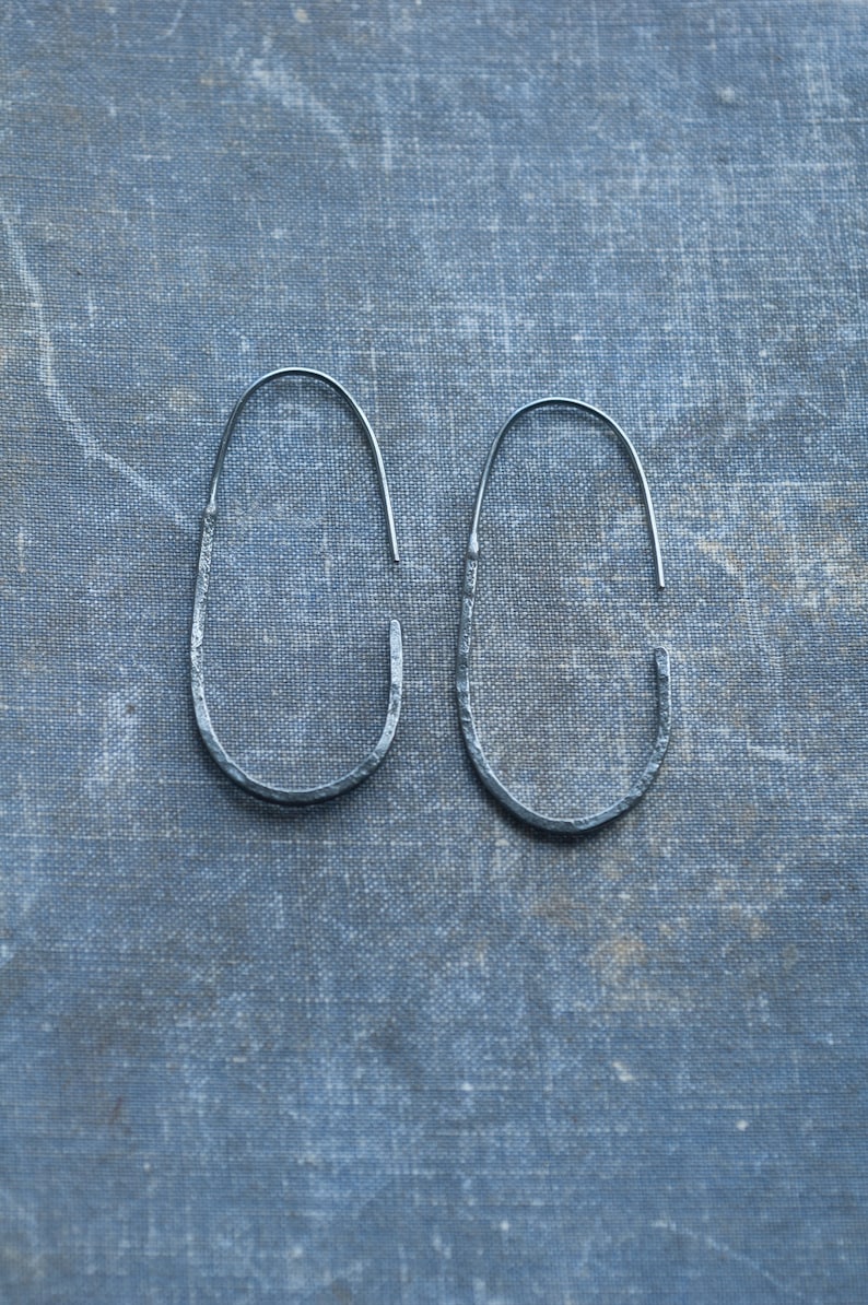 Pu&ograve; includere: Un paio di orecchini a cerchio ovali in argento con una texture martellata.