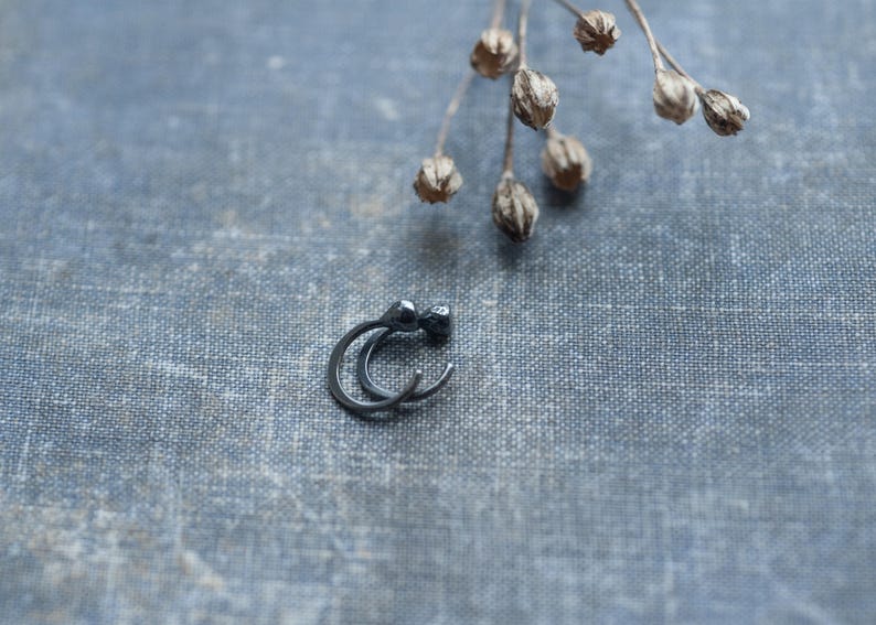 May include: A pair of black hoop earrings with a small ball at the top of each hoop.