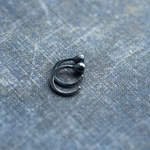 May include: A pair of black hoop earrings with a smooth, rounded finish.