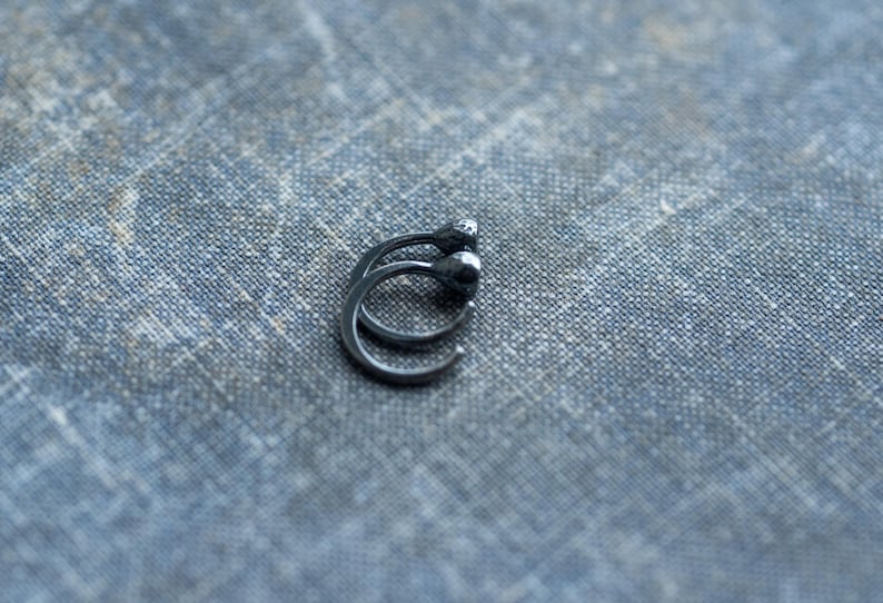 May include: A pair of black hoop earrings with a smooth, rounded finish.