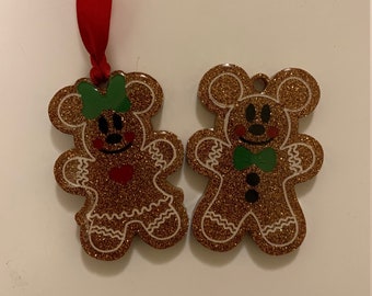 Puede incluir: Dos adornos de jengibre con forma de Mickey Mouse y Minnie Mouse. Los adornos son dorados con detalles de glaseado blanco y purpurina. Mickey Mouse lleva una pajarita verde y Minnie Mouse lleva un lazo verde.