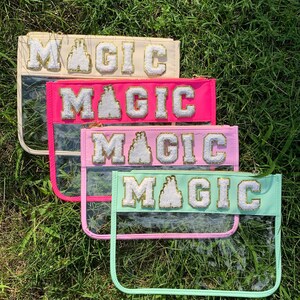 May include: Four clear plastic zippered pouches with a gold glitter and white felt "MAGIC" patch on each. The pouches are stacked on top of each other, with the top pouch being beige, the second pouch being pink, the third pouch being light pink, and the bottom pouch being light green.