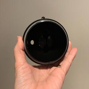 May include: Black plastic lid with a small hole in the centre. The lid has a silver ring around the edge.