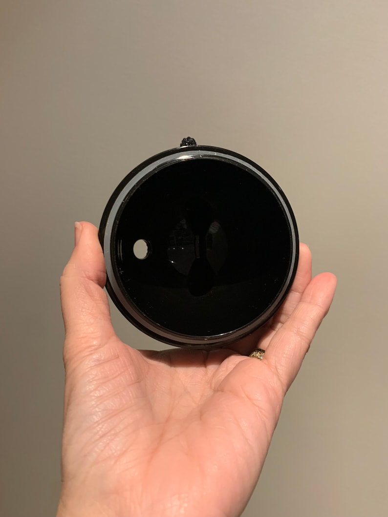 May include: Black plastic lid with a small hole in the centre. The lid has a silver ring around the edge.