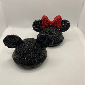May include: Two black and red rhinestone Mickey Mouse and Minnie Mouse bottle stoppers. The Minnie Mouse bottle stopper has a red rhinestone bow.