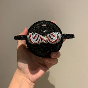 May include: A black and white rhinestone Mickey Mouse head with a red and green striped bow.