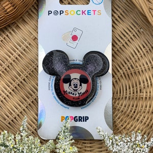 May include: A black and red PopSocket phone grip with a glitter finish. The PopSocket features a Mickey Mouse Club logo with Mickey Mouse in the centre. The text "PopGrip" is printed in white on the bottom of the packaging.