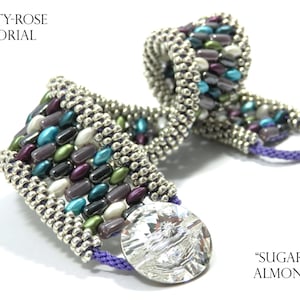 May include: A multi-coloured beaded bracelet with a silver clasp and a crystal button. The bracelet is made with a variety of beads, including turquoise, purple, green, and silver. The bracelet is called "Sugered Almonds".