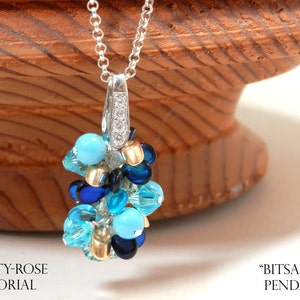 May include: A silver chain necklace with a pendant made of blue, turquoise, and gold beads. The pendant is shaped like a cluster of grapes.