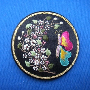美しい刺繍のピンク、ブルー、イエローの蝶、ピンク、ホワイトの花の円形ファッションピンブローチ