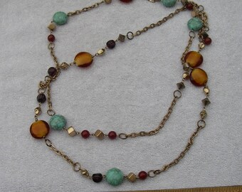 May include: A long gold chain necklace with amber, turquoise, and burgundy beads. The necklace is layered and has a variety of different sized beads.