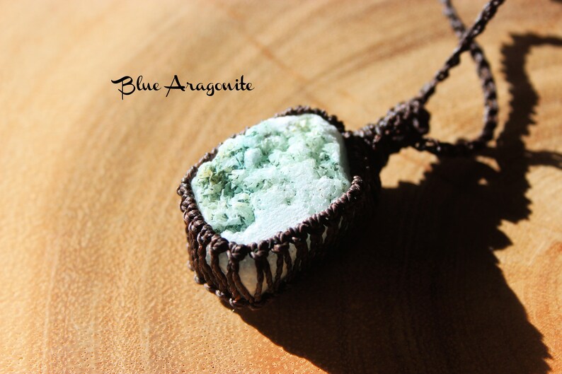 K&ouml;nnte beinhalten: Ein blauer Aragonit-Anh&auml;nger, umwickelt mit braunem Kordel, mit dem Text "Blue Aragonite" dar&uuml;ber.