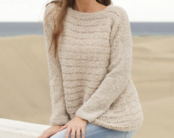 May include: A light beige knit sweater with a crew neck and long sleeves. The sweater has a textured appearance and is worn with light blue jeans. The image includes the text "DROPS DESIGN" and "www.garnstudio.com".