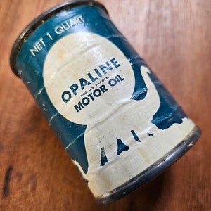 May include: A vintage, blue and white, one-quart can of Opalene Motor Oil. The can features an elephant graphic and the text "Opalene Motor Oil, Reg. U.S. Pat. Off."