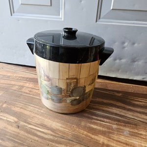 May include: A black and brown plastic cooler with a woodgrain pattern and a picture of kitchen utensils. The cooler has a black lid with a handle.