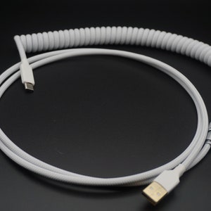 May include: White coiled USB cable with a USB-C connector on one end and a USB-A connector on the other end.
