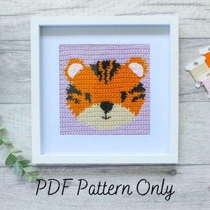May include: A framed crochet pattern of a tiger face using orange, black and white yarn. The frame is white and the background is light purple. The text "PDF Pattern Only" is below the frame.
