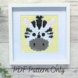 May include: A framed crochet pattern of a zebra face with black and white stripes, a gray nose, and pink ears. The background is yellow. The text "PDF Pattern Only" is below the frame.