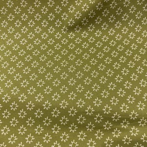 May include: Olive green fabric with a repeating pattern of white, stylized floral shapes. The fabric has a slightly textured appearance, with the white designs evenly spaced across the surface. The overall effect is a classic, decorative textile.