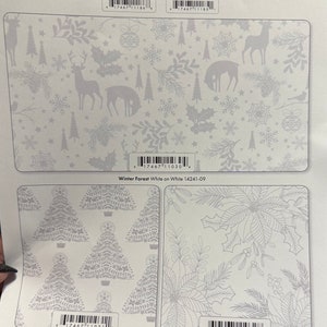 K&ouml;nnte beinhalten: Ein wei&szlig;er Stoff mit einem silbernen Schneeflocken- und Winterwald-Design. Der Stoff ist mit "Holiday Snow" beschriftet und Teil der Benartex Kanvas-Kollektion. Der Stoff ist in zwei Gr&ouml;&szlig;en erh&auml;ltlich: 15 Yards und 10 Yards.