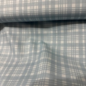 May include: Close-up of a light blue and white plaid fabric. The fabric has a repeating pattern of intersecting lines, creating a grid-like design. The fabric is folded, showing the texture and drape of the material. Ideal for sewing projects.