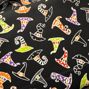 May include: Black fabric with a repeating pattern of colorful witch hats. The hats are in various styles and colors, including green, orange, purple, and red.